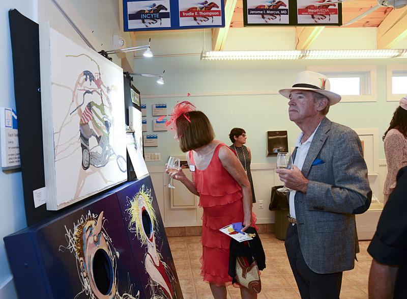 Sporting a classy fascinator is Lexi Ellis and Bill Ellis dons a Panama hat as they peruse the art exhibition.
